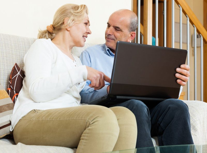 Smiling mature couple with laptop